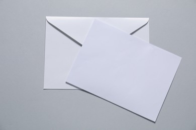 Photo of Paper envelope with letter on gray background, top view. Mockup for design