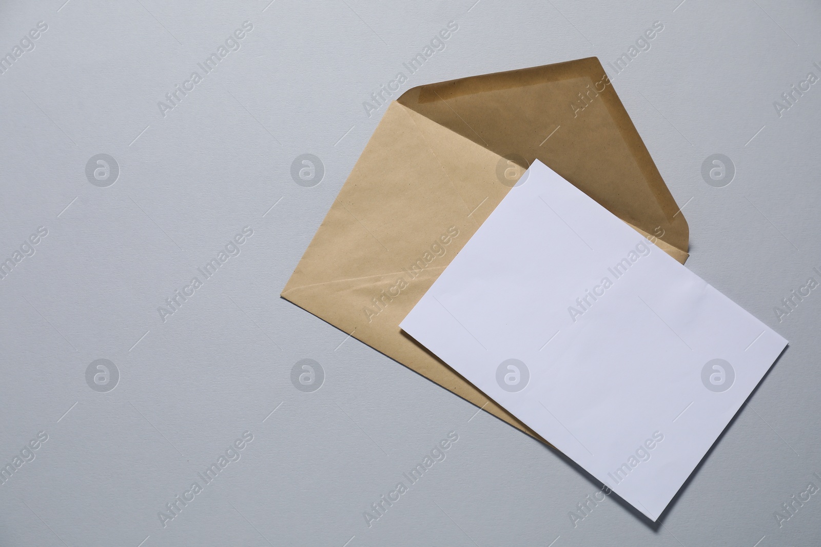 Photo of Kraft paper envelope with letter on gray background, top view. Mockup for design