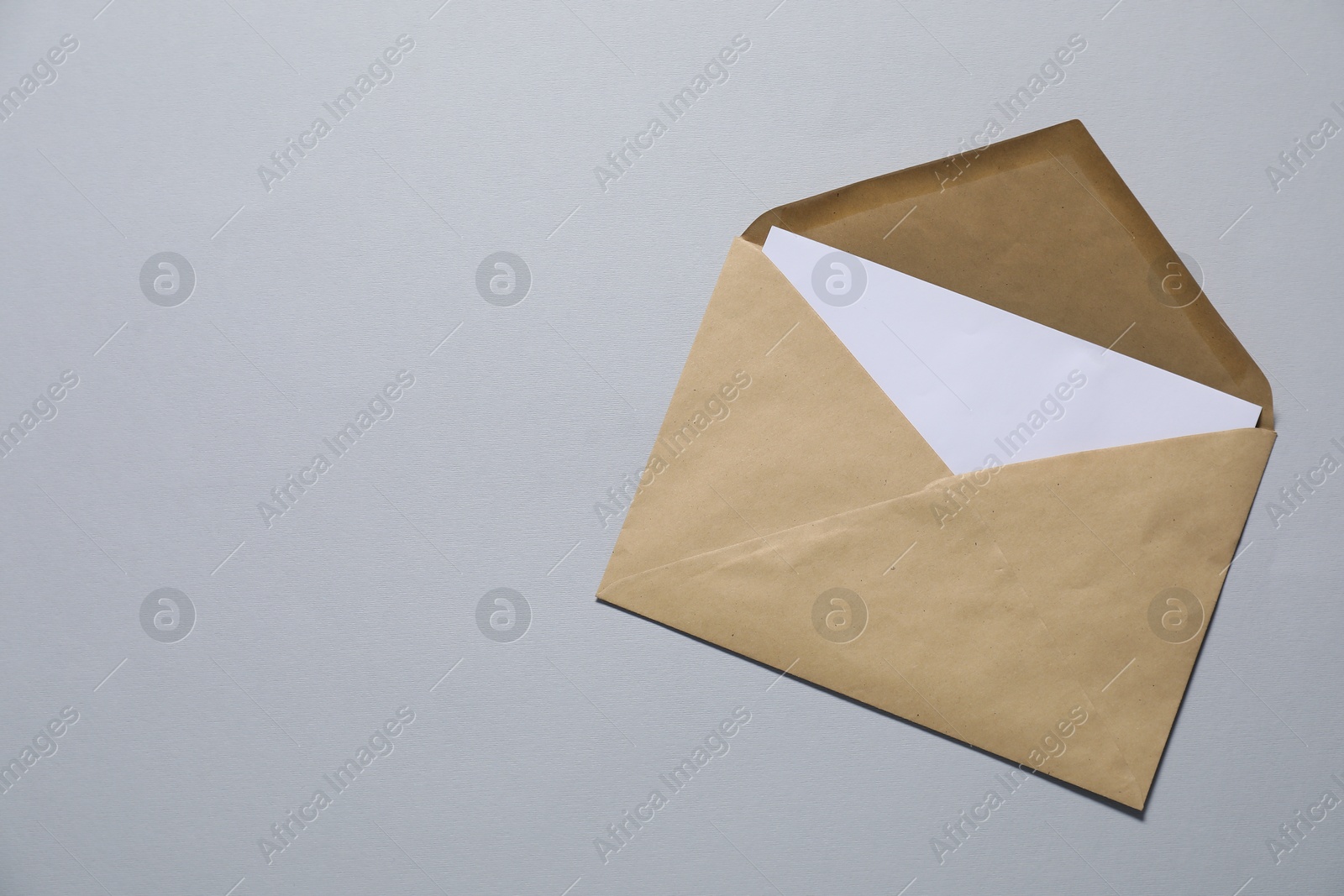 Photo of Kraft paper envelope with letter on gray background, top view. Mockup for design