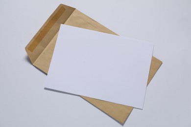 Photo of Kraft paper envelope with letter on white background, top view. Mockup for design