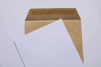 Photo of Kraft paper envelope with letter on white background, top view. Mockup for design