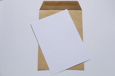 Photo of Kraft paper envelope with letter on white background, top view. Mockup for design