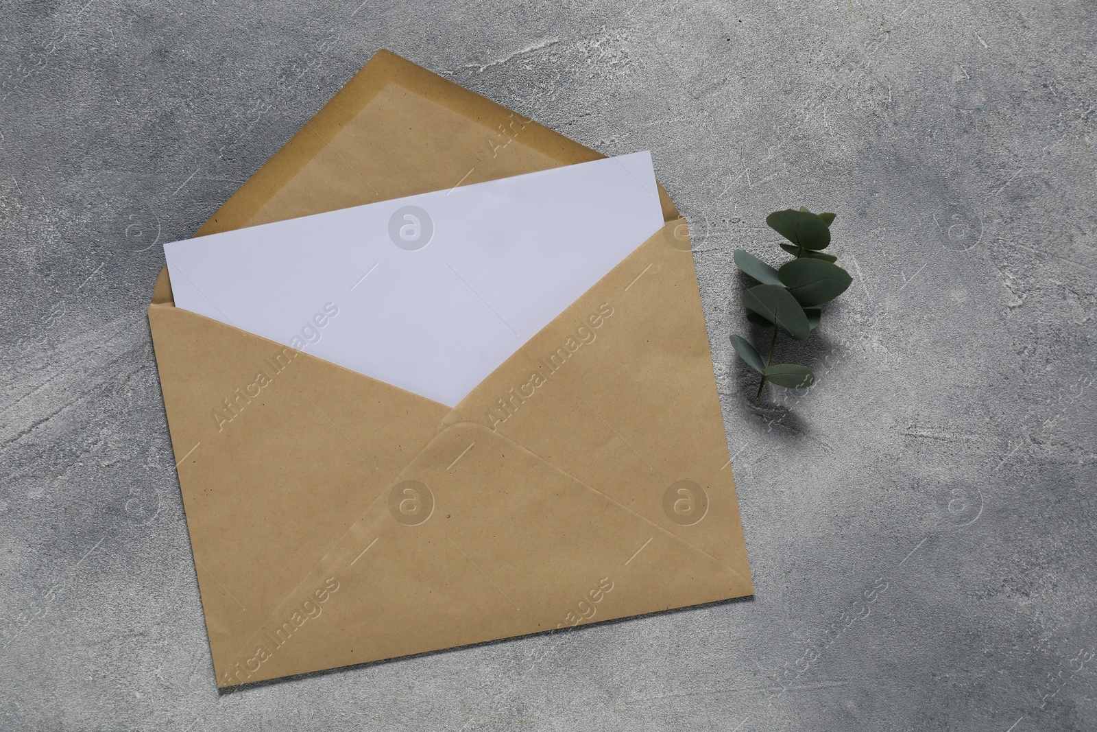 Photo of Paper envelope with letter and eucalyptus branch on gray textured background, flat lay. Mockup for design