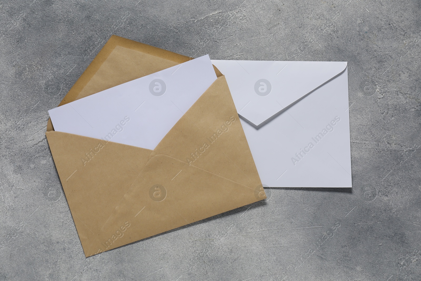 Photo of Paper envelopes with letter on gray textured background, top view. Mockup for design