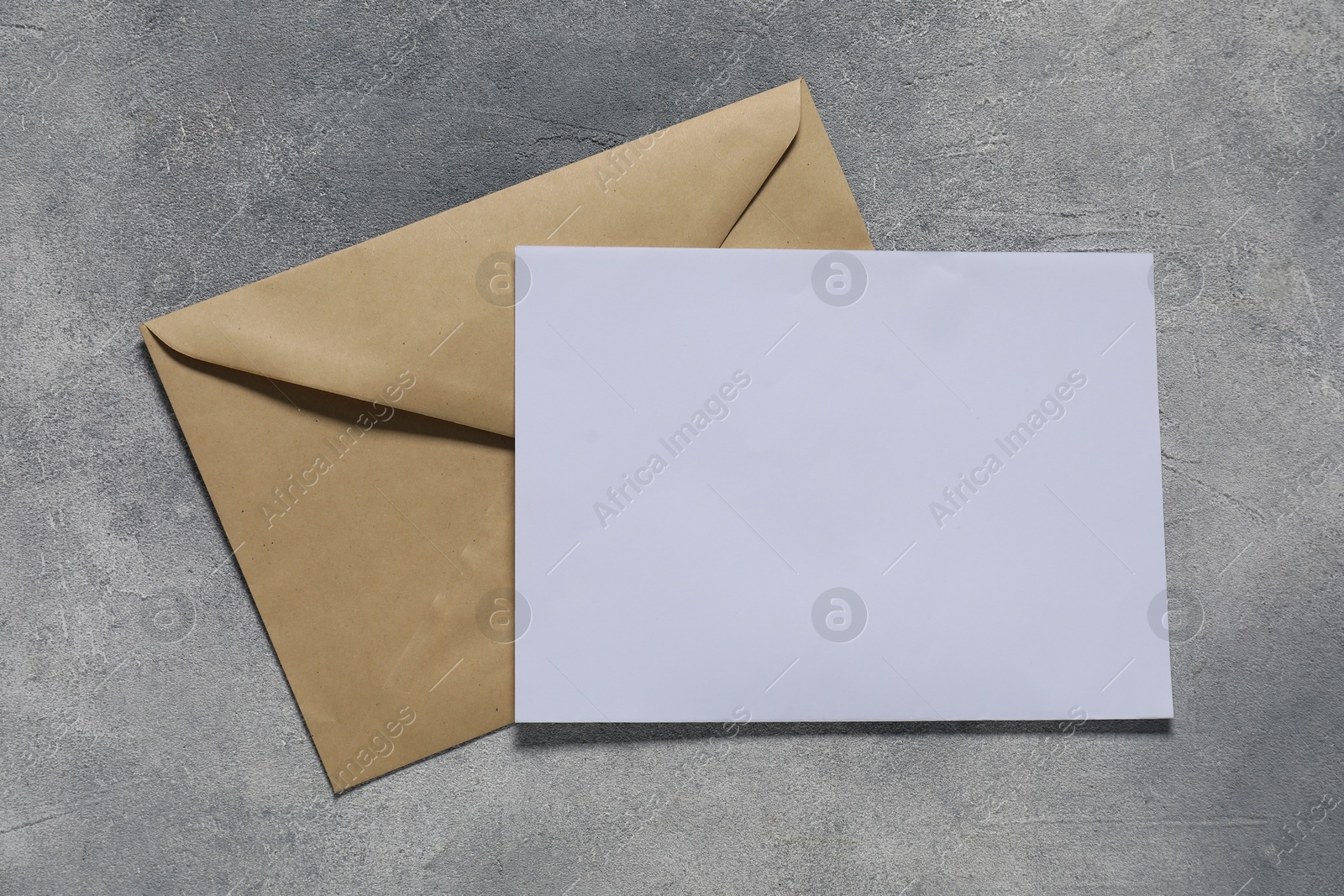 Photo of Paper envelope with letter on gray textured background, top view. Mockup for design