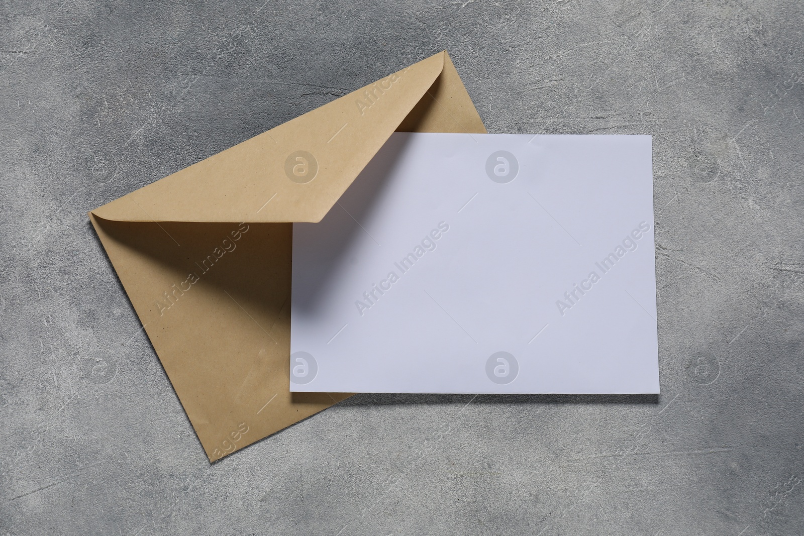 Photo of Paper envelope with letter on gray textured background, top view. Mockup for design