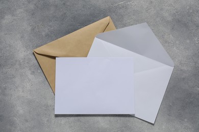 Photo of Paper envelopes with letter on gray textured background, top view. Mockup for design