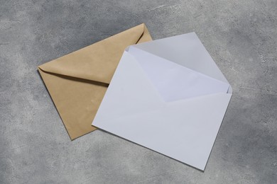 Photo of Paper envelopes with letter on gray textured background, top view. Mockup for design