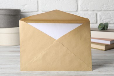 Photo of Kraft paper envelope with letter on wooden table, closeup. Mockup for design