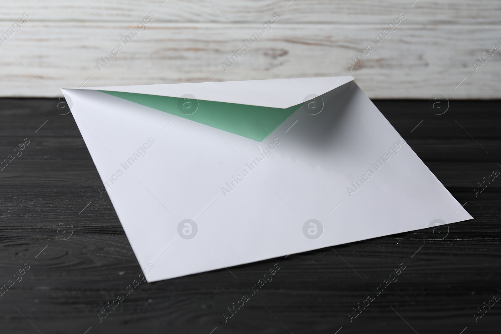 Photo of Paper envelope with letter on black wooden table. Mockup for design