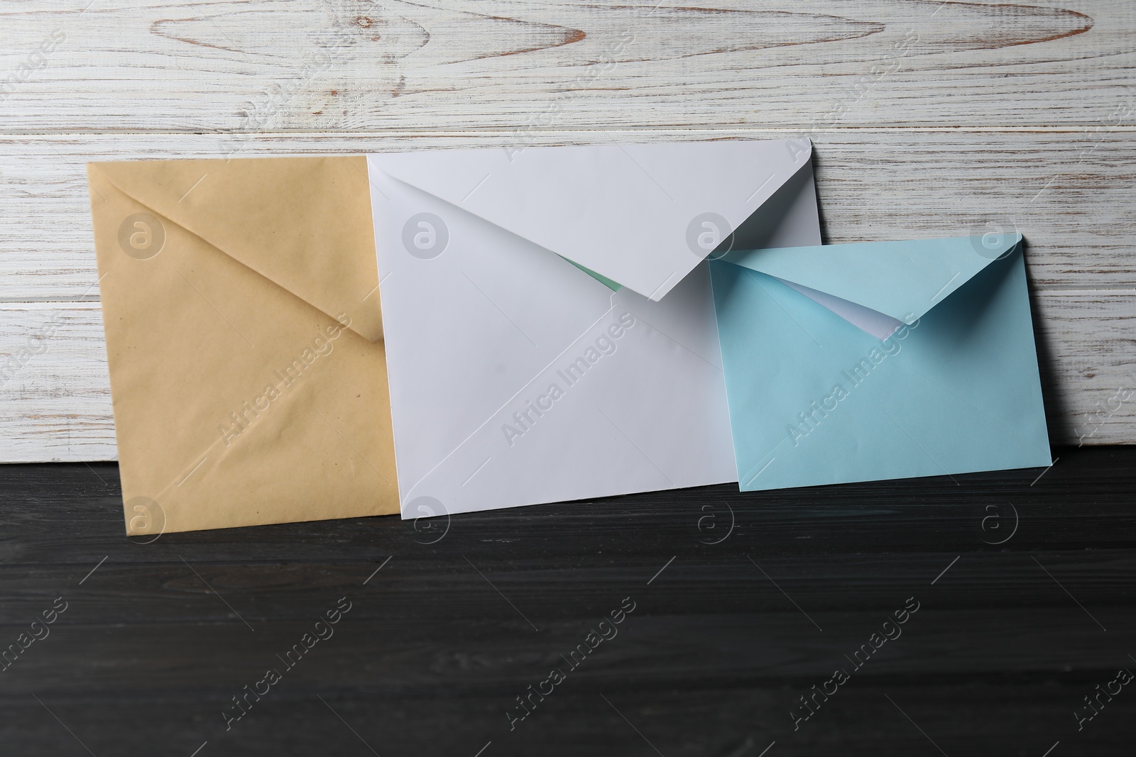 Photo of Paper envelopes on black wooden table. Mockup for design