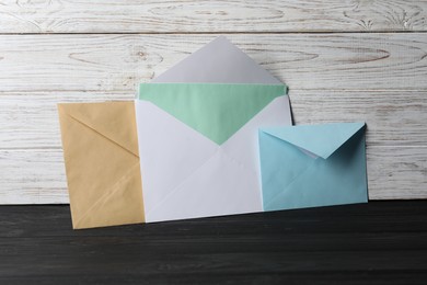 Paper envelopes with letter on black wooden table. Mockup for design