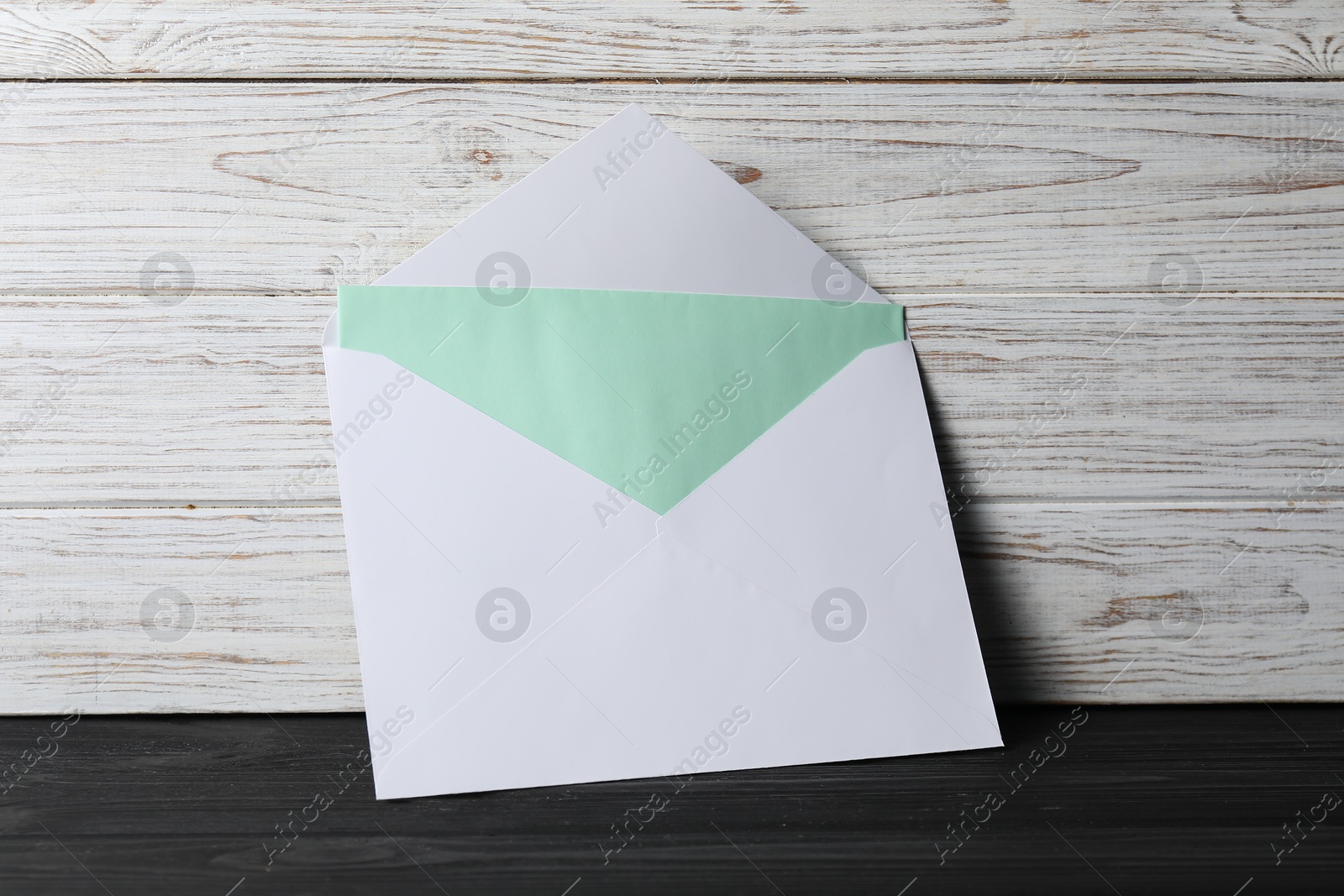 Photo of Paper envelope with letter on black wooden table. Mockup for design