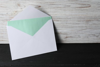 Photo of Paper envelope with letter on black wooden table. Mockup for design