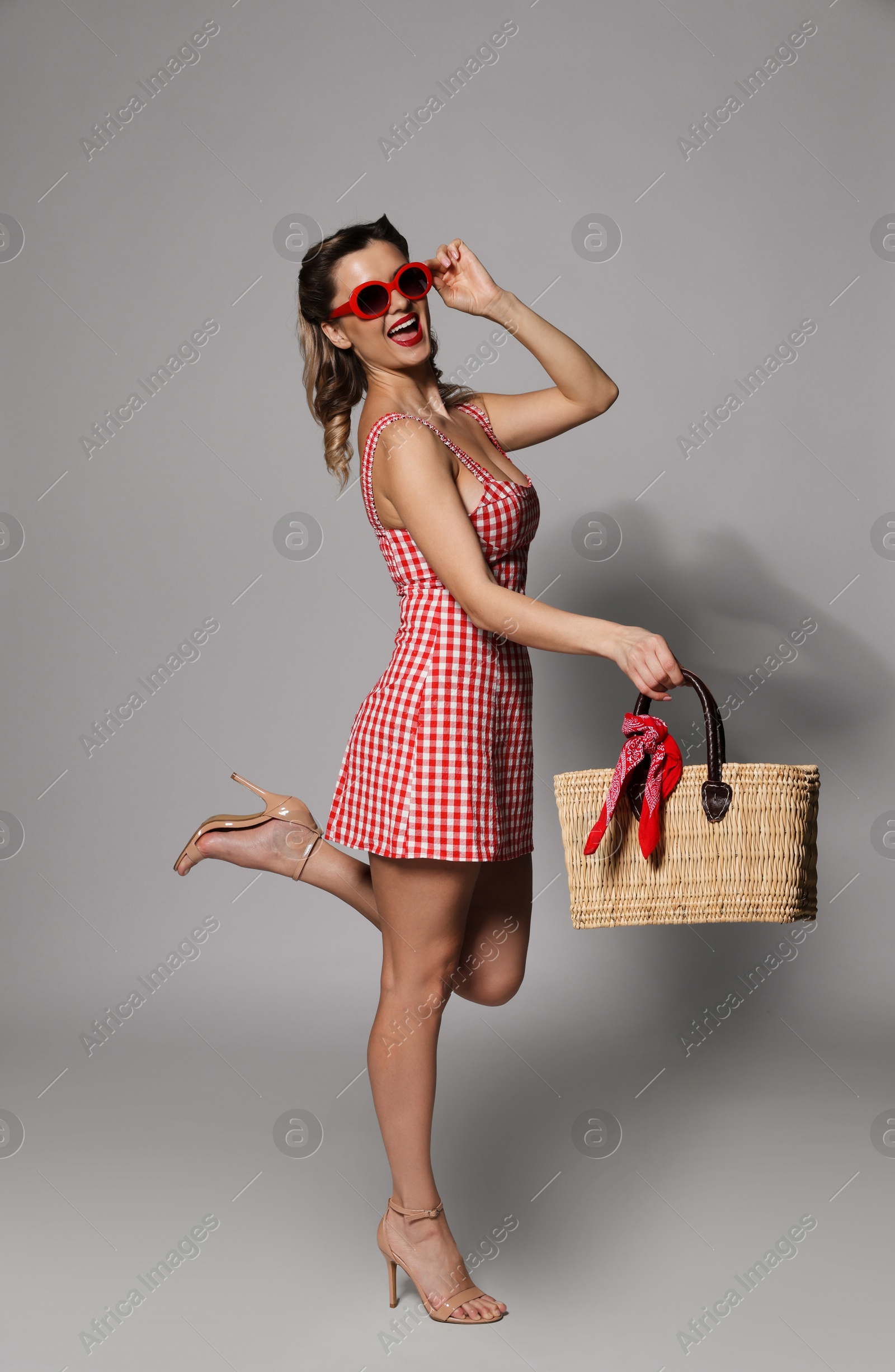 Photo of Happy pin-up woman in dress posing on grey background