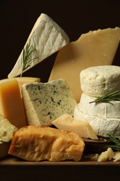 Photo of Different types of cheese and rosemary on table, closeup