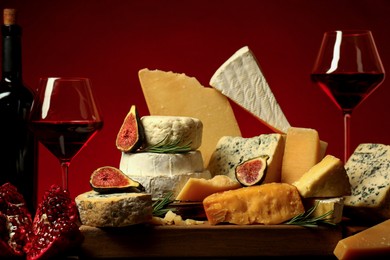 Photo of Different types of cheese, rosemary, figs, pomegranate and wine on table