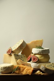 Photo of Different types of cheese, figs and rosemary on table