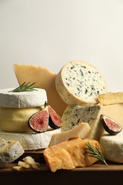 Photo of Different types of cheese, figs and rosemary on table, closeup