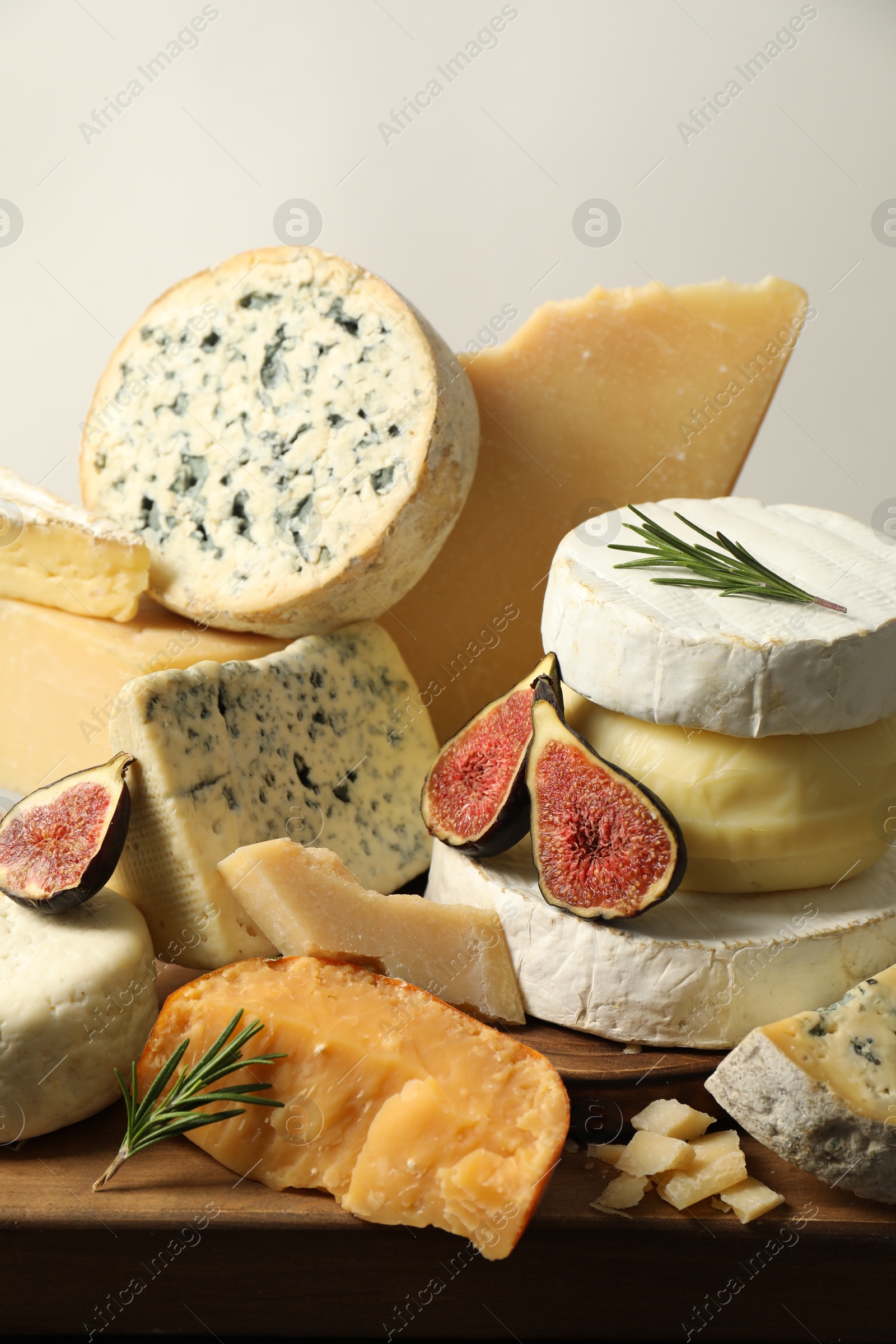 Photo of Different types of cheese, figs and rosemary on table, closeup