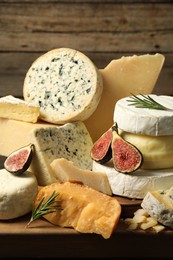 Photo of Different types of cheese, figs and rosemary on table, closeup