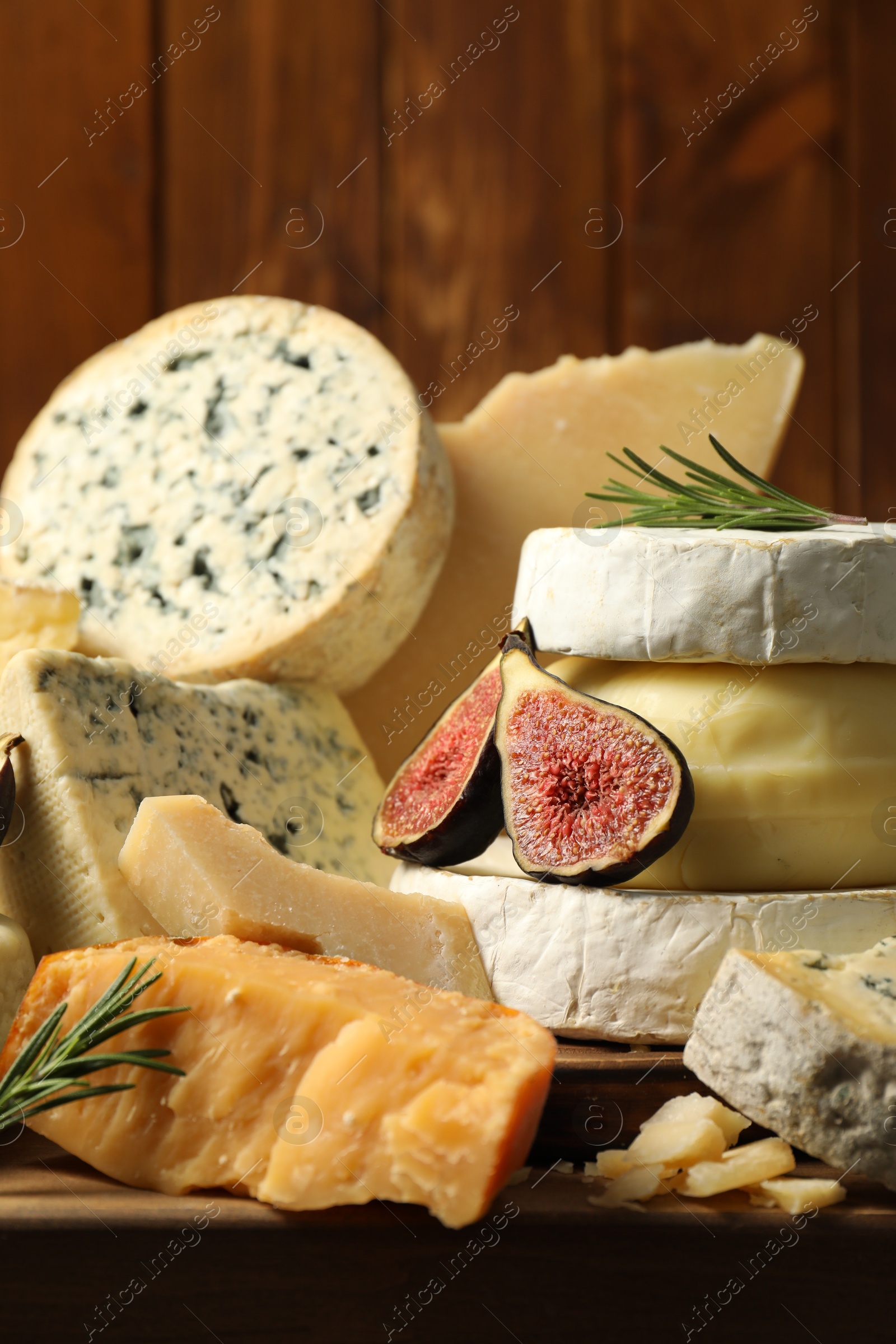 Photo of Different types of cheese, figs and rosemary on table, closeup