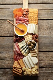 Photo of Different types of delicious cheese and other snacks on wooden table, top view