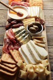 Photo of Different types of delicious cheese and other snacks on wooden table, closeup