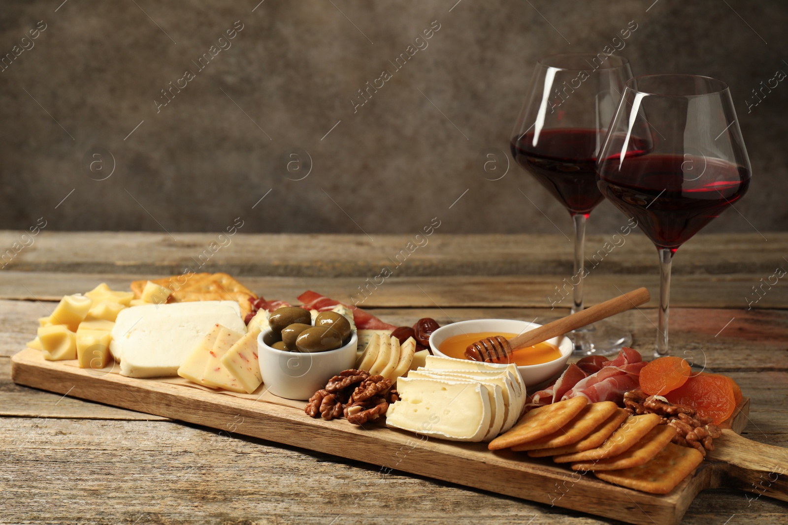 Photo of Different types of delicious cheese, other snacks and wine on wooden table