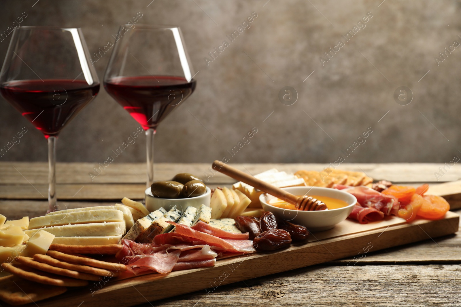 Photo of Different types of delicious cheese, other snacks and wine on wooden table, closeup