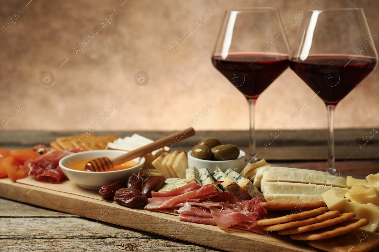 Photo of Different types of delicious cheese, other snacks and wine on wooden table, closeup