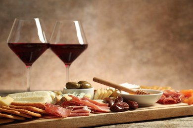 Photo of Different types of delicious cheese, other snacks and wine on wooden table, closeup