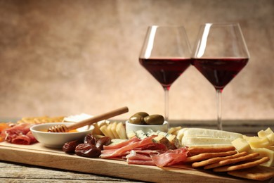 Photo of Different types of delicious cheese, other snacks and wine on wooden table, closeup