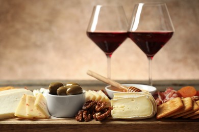 Photo of Different types of delicious cheese, other snacks and wine on table, closeup