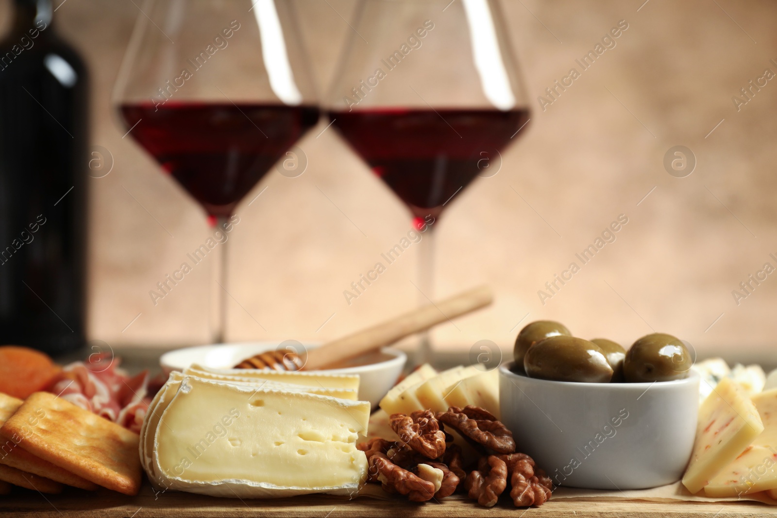 Photo of Different types of delicious cheese, other snacks and wine on table, closeup