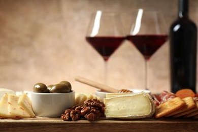 Photo of Different types of delicious cheese, other snacks and wine on table, closeup