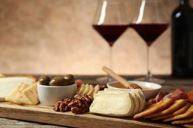 Photo of Different types of delicious cheese, other snacks and wine on table, closeup