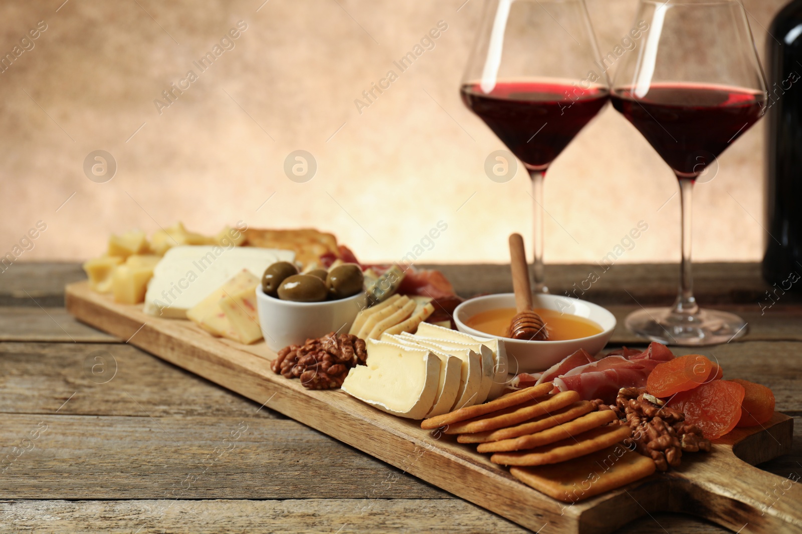 Photo of Different types of delicious cheese, other snacks and wine on wooden table, closeup