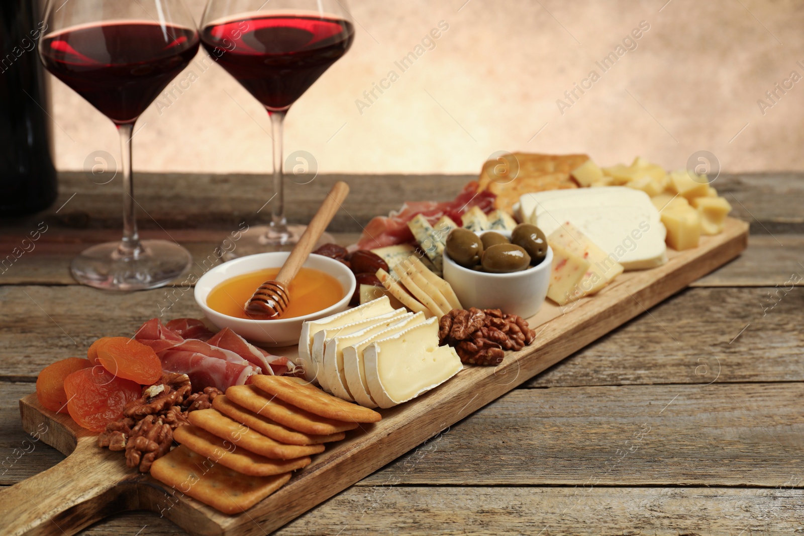 Photo of Different types of delicious cheese, other snacks and wine on wooden table, closeup