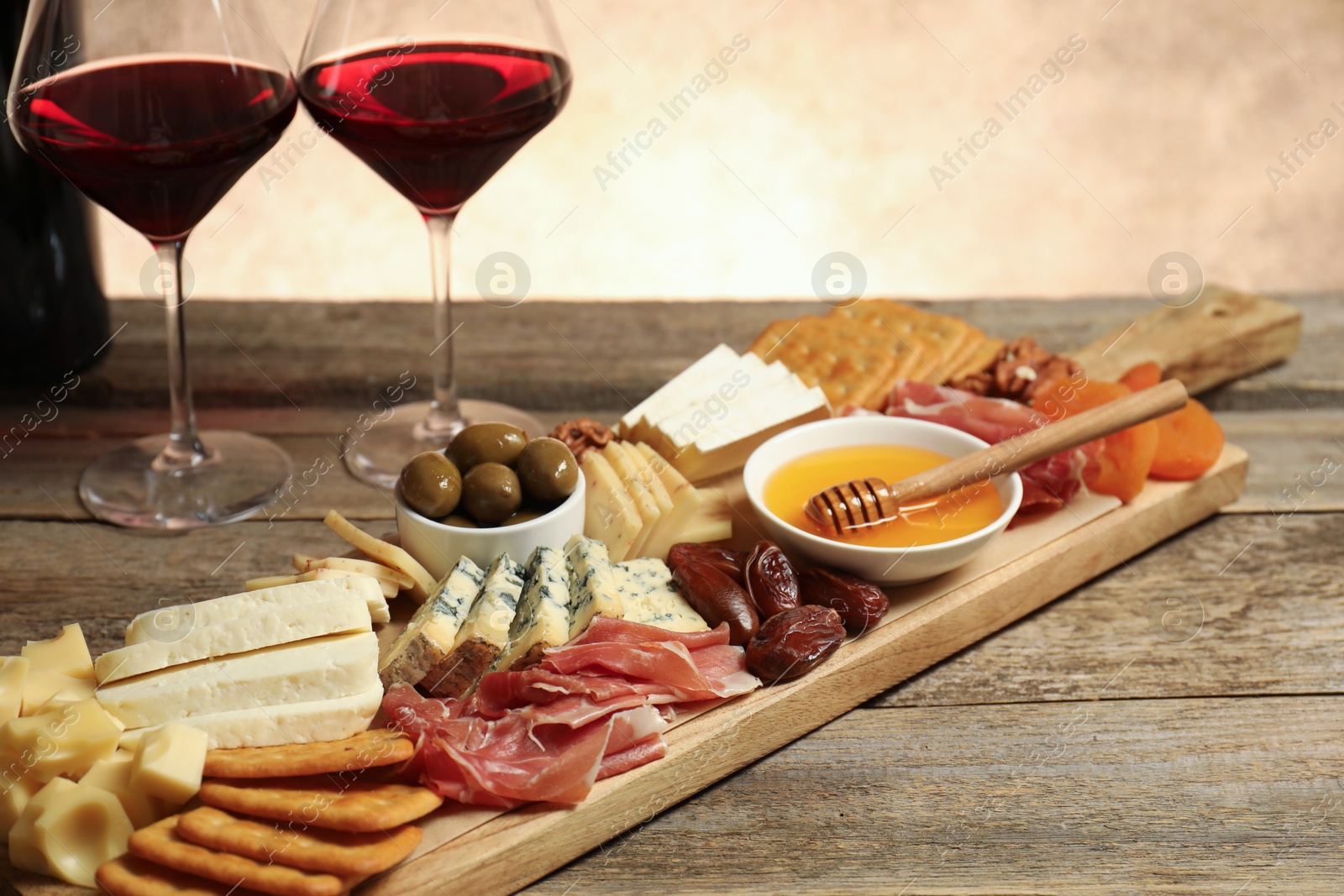 Photo of Different types of delicious cheese, other snacks and wine on wooden table, closeup