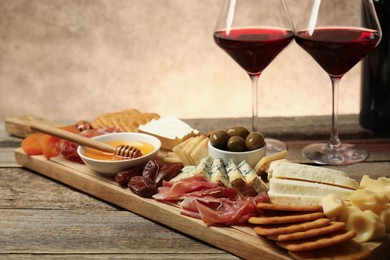 Photo of Different types of delicious cheese, other snacks and wine on wooden table, closeup