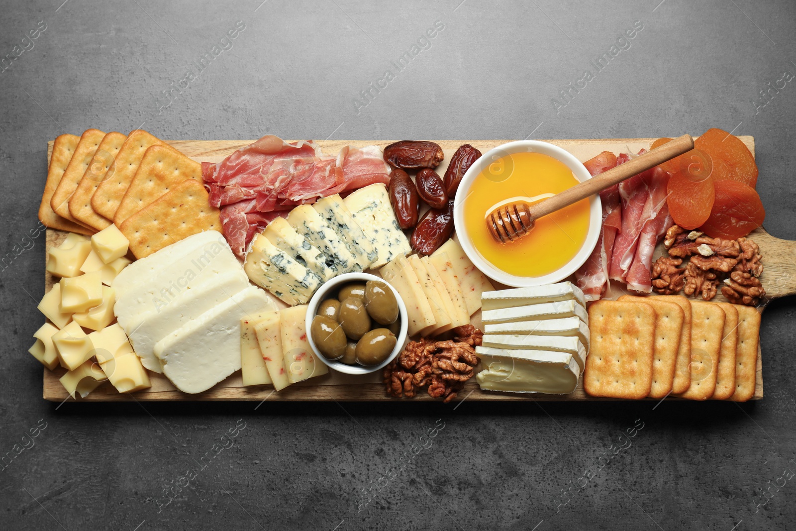 Photo of Different types of delicious cheese and other snacks on grey table, top view