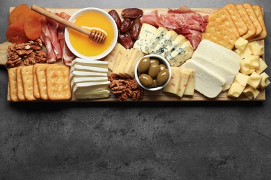 Photo of Different types of delicious cheese and other snacks on grey table, top view. Space for text