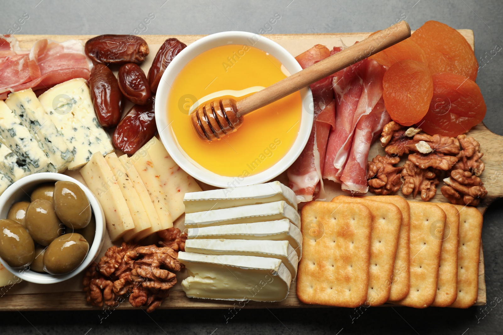 Photo of Different types of delicious cheese and other snacks on grey table, top view