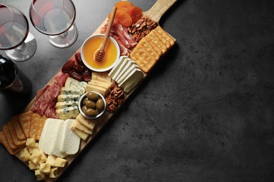 Photo of Different types of delicious cheese, other snacks and wine on grey table, flat lay. Space for text