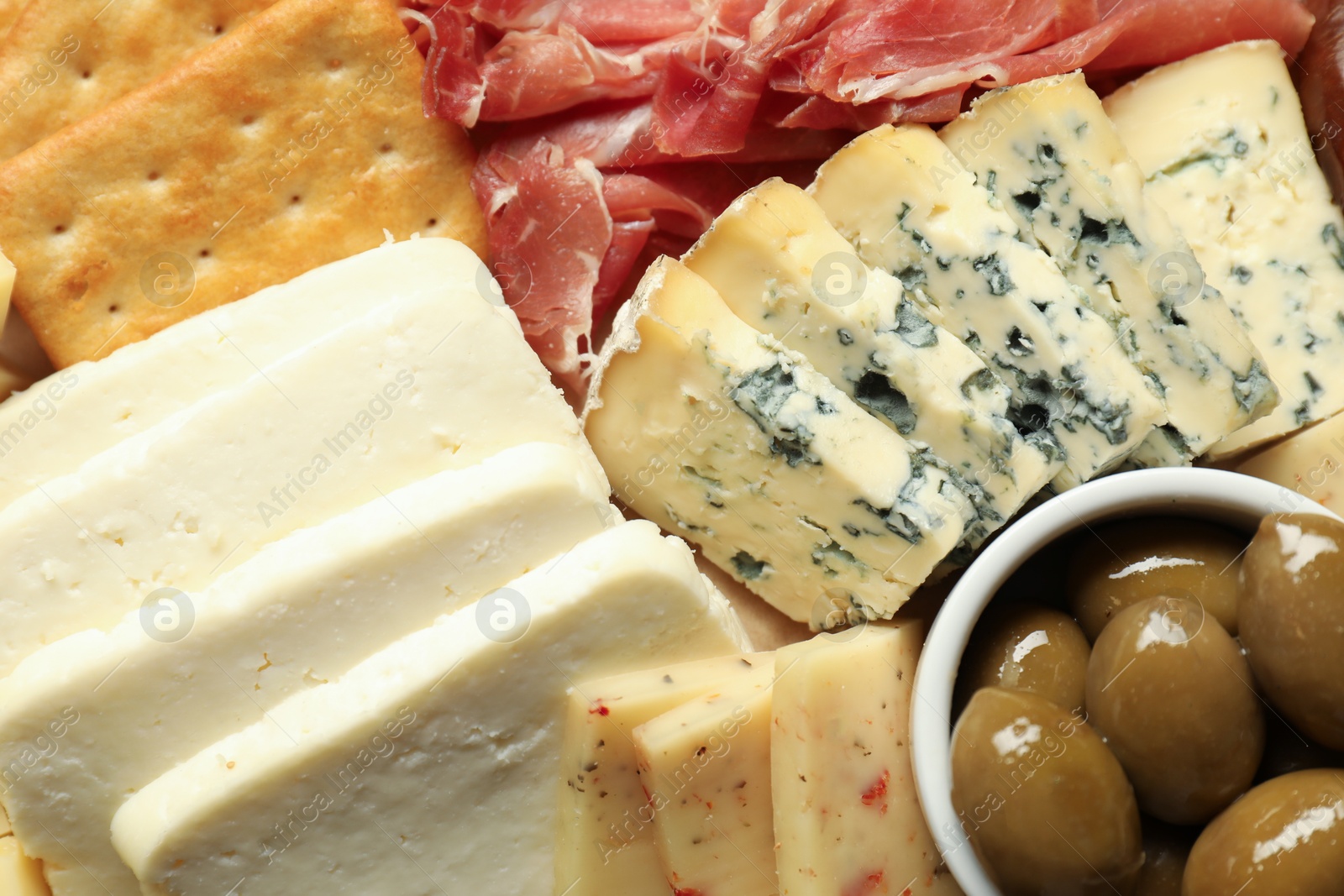 Photo of Different types of delicious cheese and other snacks as background, top view