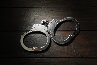 Photo of Metal chain handcuffs on wooden table, top view