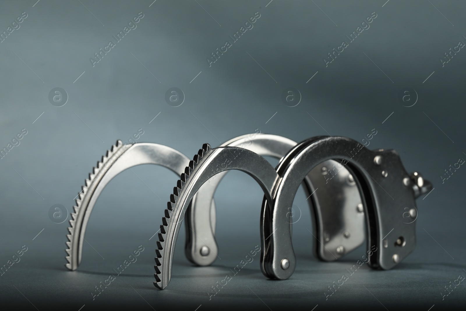 Photo of Metal chain handcuffs on grey background, closeup