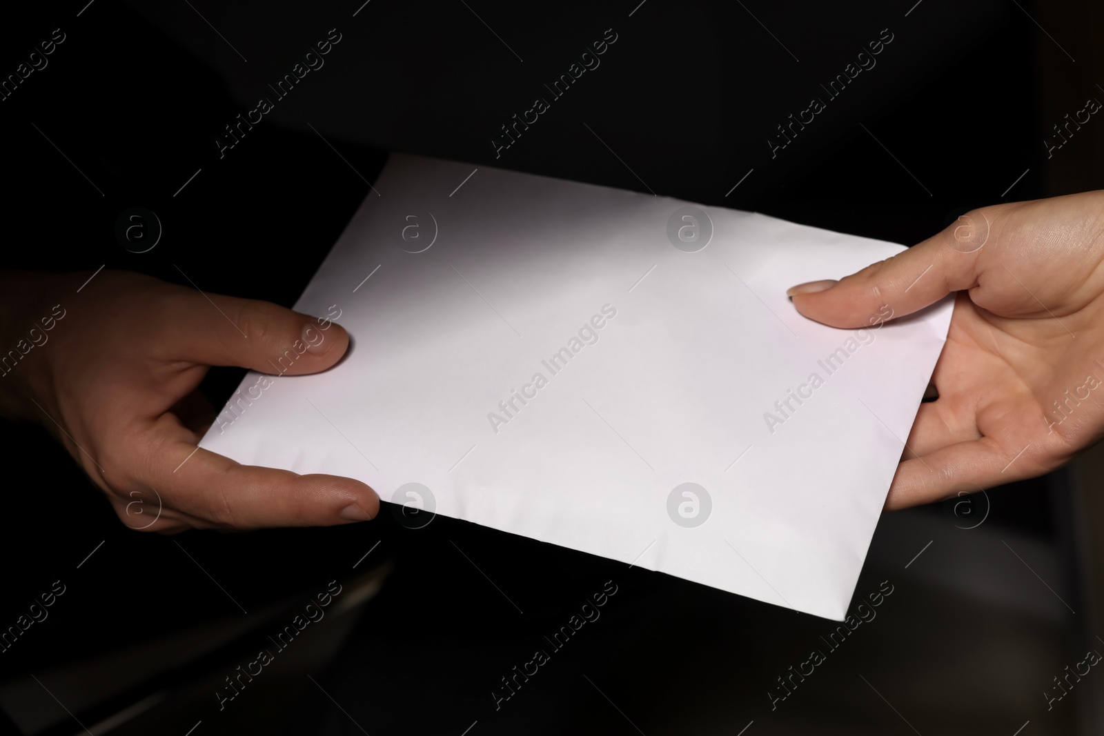 Photo of Corruption concept. Woman giving envelope with money to man on black background, closeup