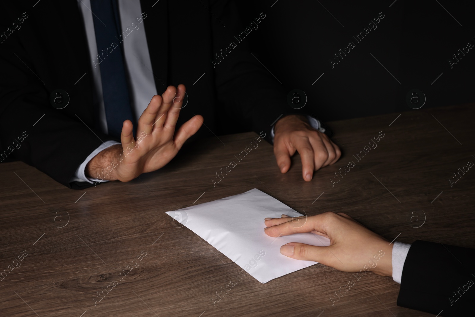 Photo of Corruption concept. Woman giving envelope with money to man at wooden table, closeup